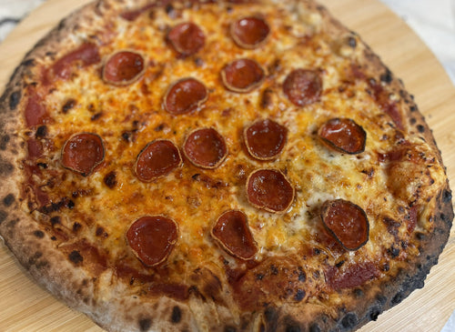 Cupped pepperoni pizza fresh from a wood-fired oven with roni cups and hot honey drizzle